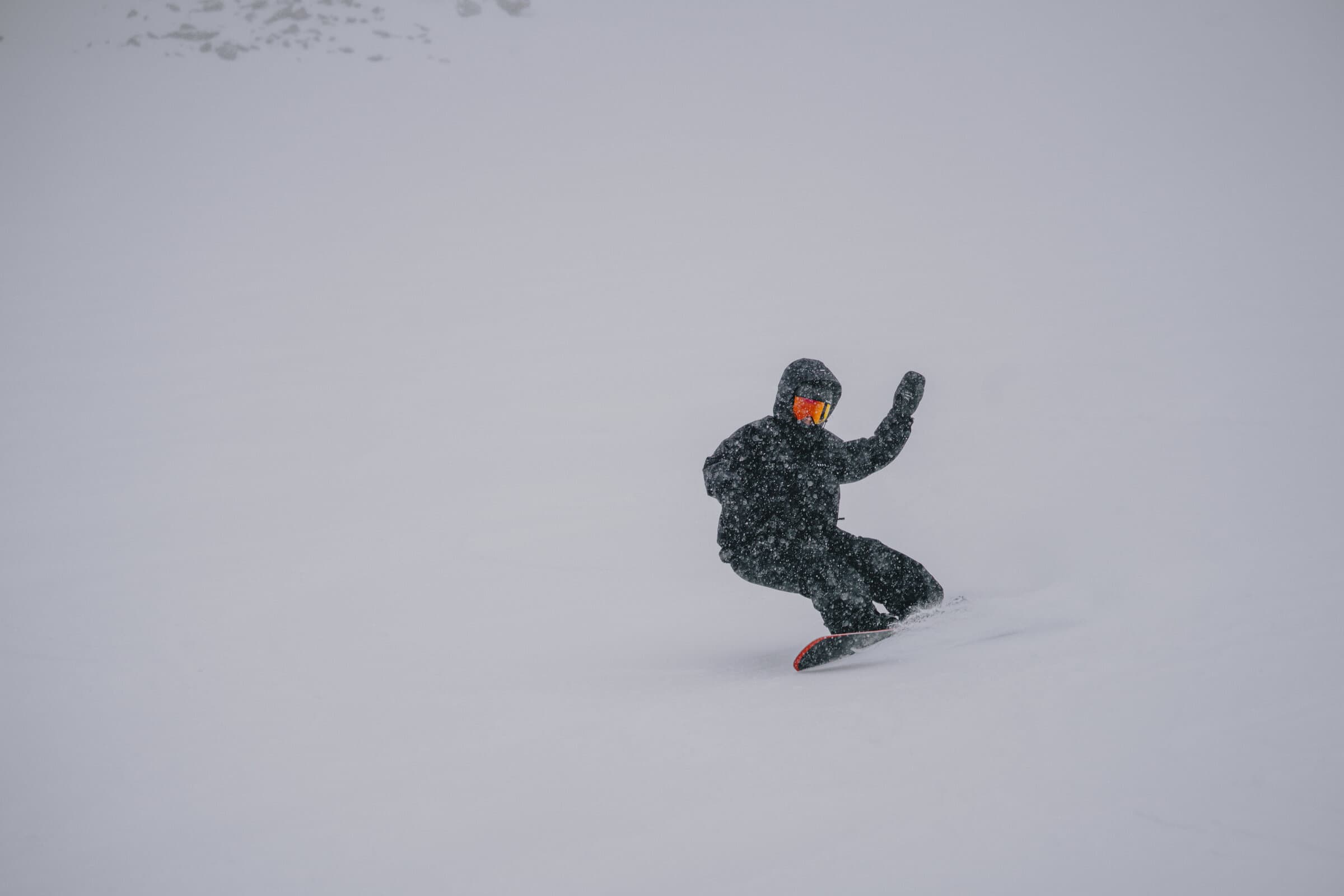 Snowboarder riding powder with Clew bindings